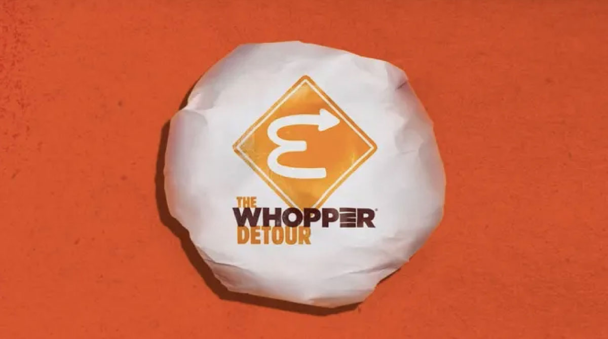 Wrapped Burger King Whopper with an orange detour road sign icon and the text The Whopper Detour on an orange background