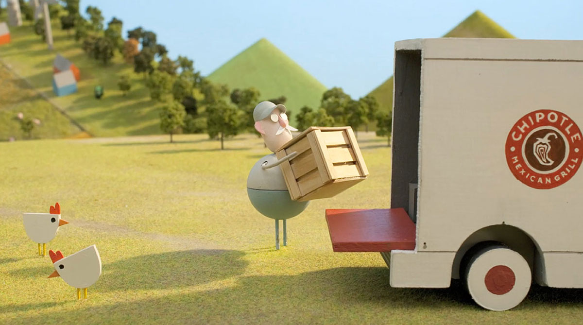 Stop-motion farmer loading a wooden crate into a Chipotle Mexican Grill truck with chickens on green hills