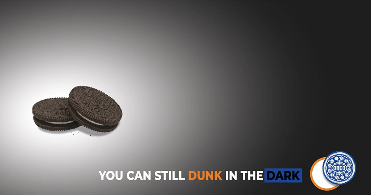 Two Oreo cookies in a spotlight on a dark background with the text You Can Still Dunk in the Dark and the Oreo logo